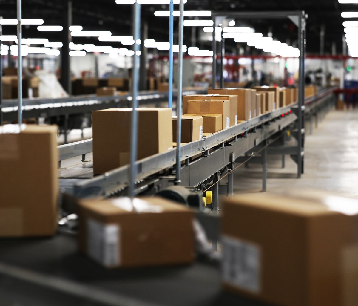 A photo of right-sized packages produced on a Packsize solution, travelling down a conveyor in a warehouse